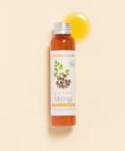 Huile de Moringa Aroma-Zone sur fond beige avec une goutte d'huile