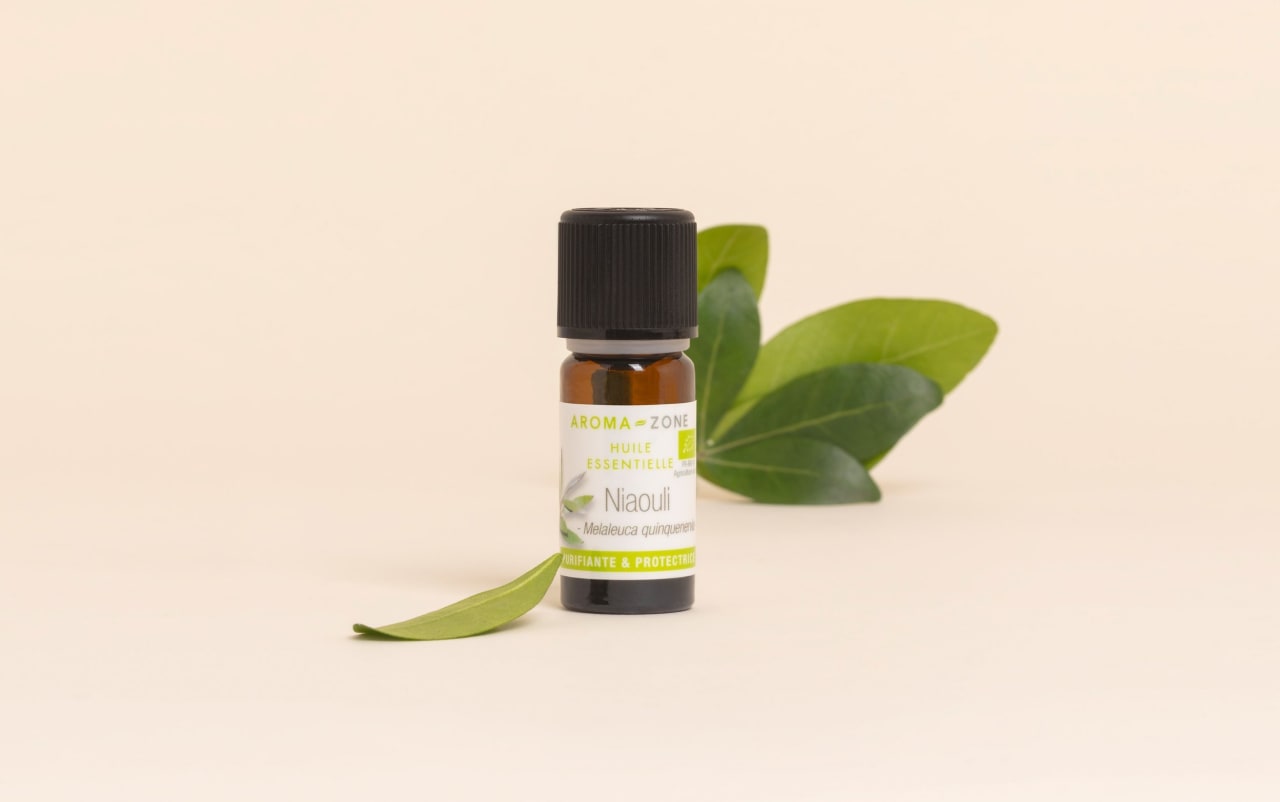 Huile essentielle de niaouli Aroma-Zone avec feuille sur fond beige